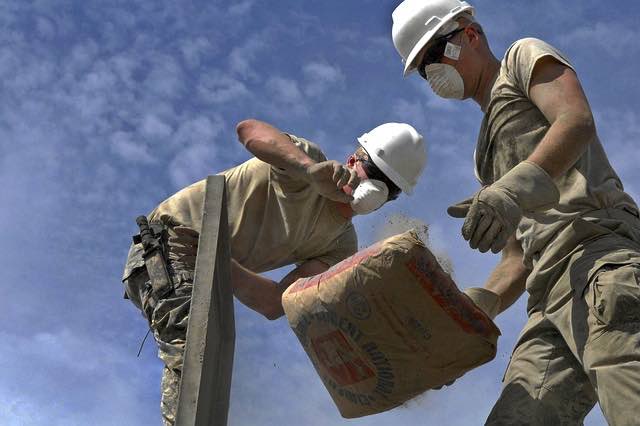 Image of workers passing bag wearing masks